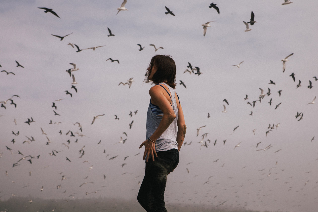 Full length rear view of woman flying birds