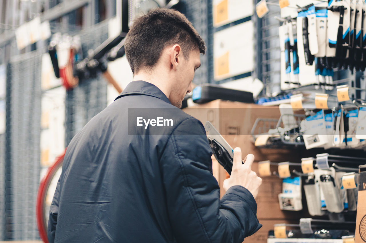 A young man inspects goods in a store.