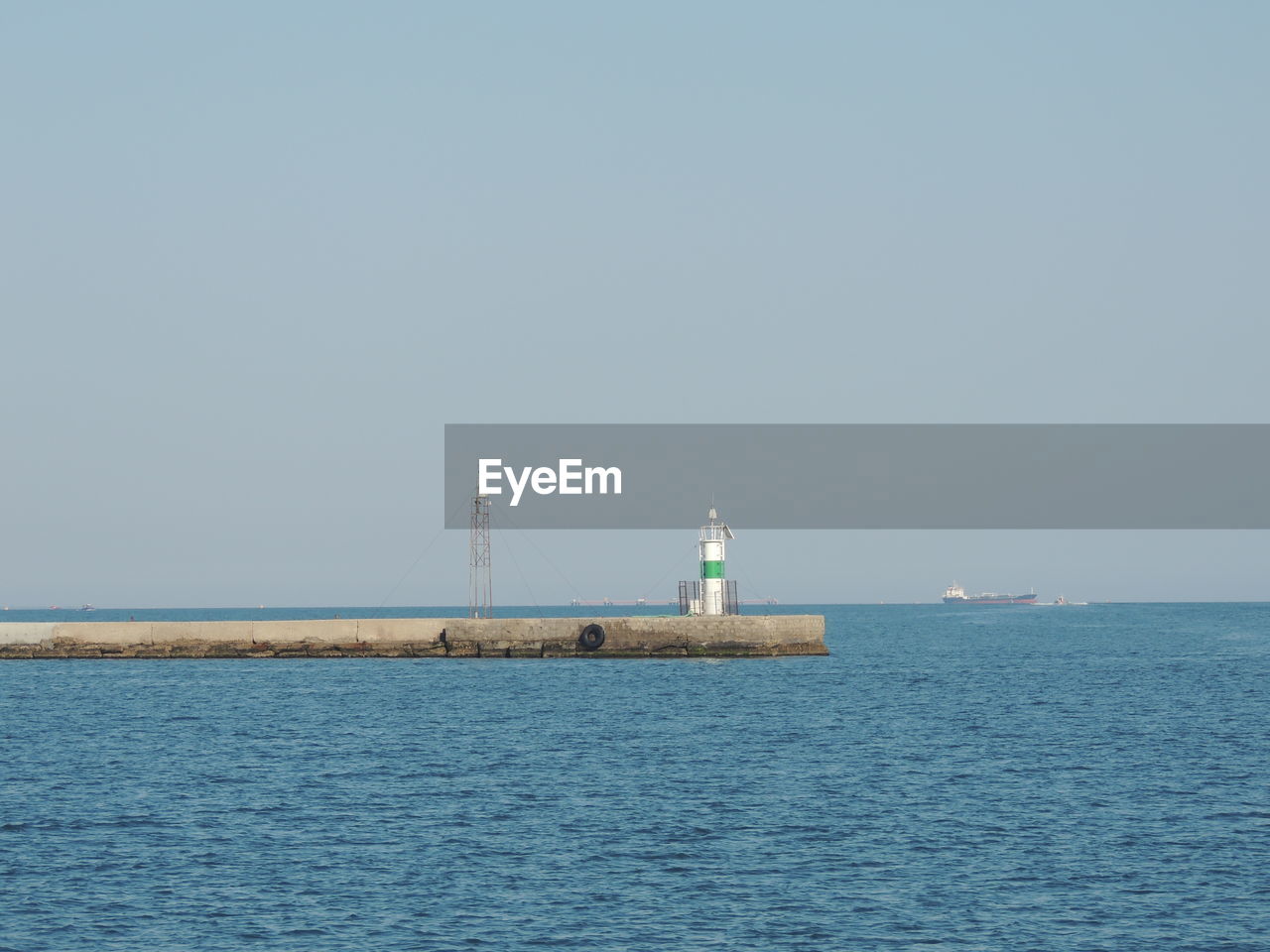 Lighthouse by sea against clear sky