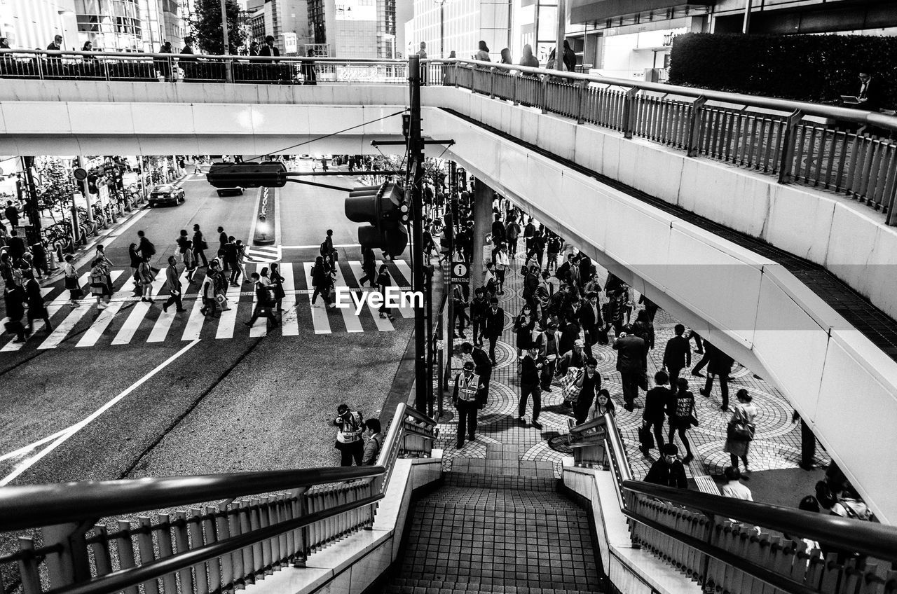 High angle view of people walking on city street over bridge