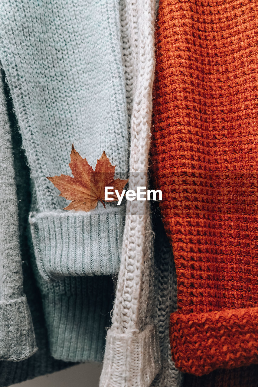 Stack of cozy knitted warm sweater with autumn fall maple leaf. sweaters in retro style. orange 