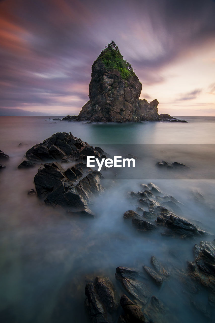 Rocks on shore against sky during sunset