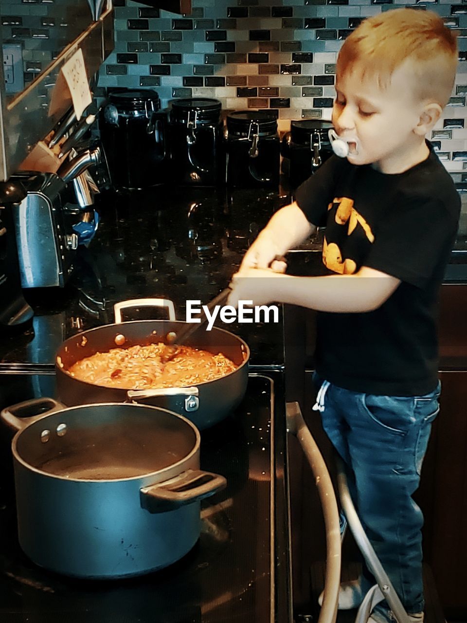 REAR VIEW OF MAN HAVING FOOD AT KITCHEN