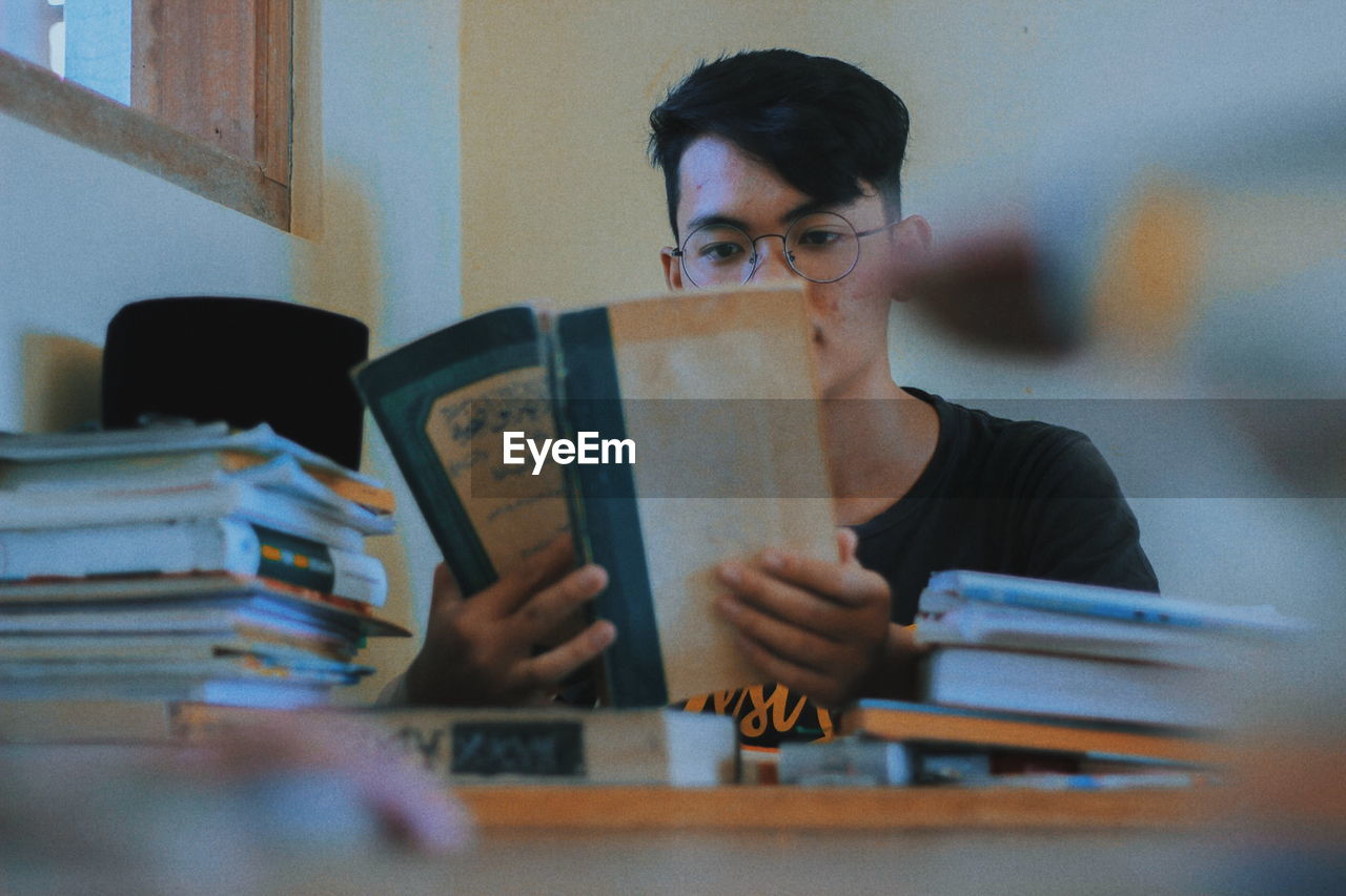 Young man reading book while sitting at home