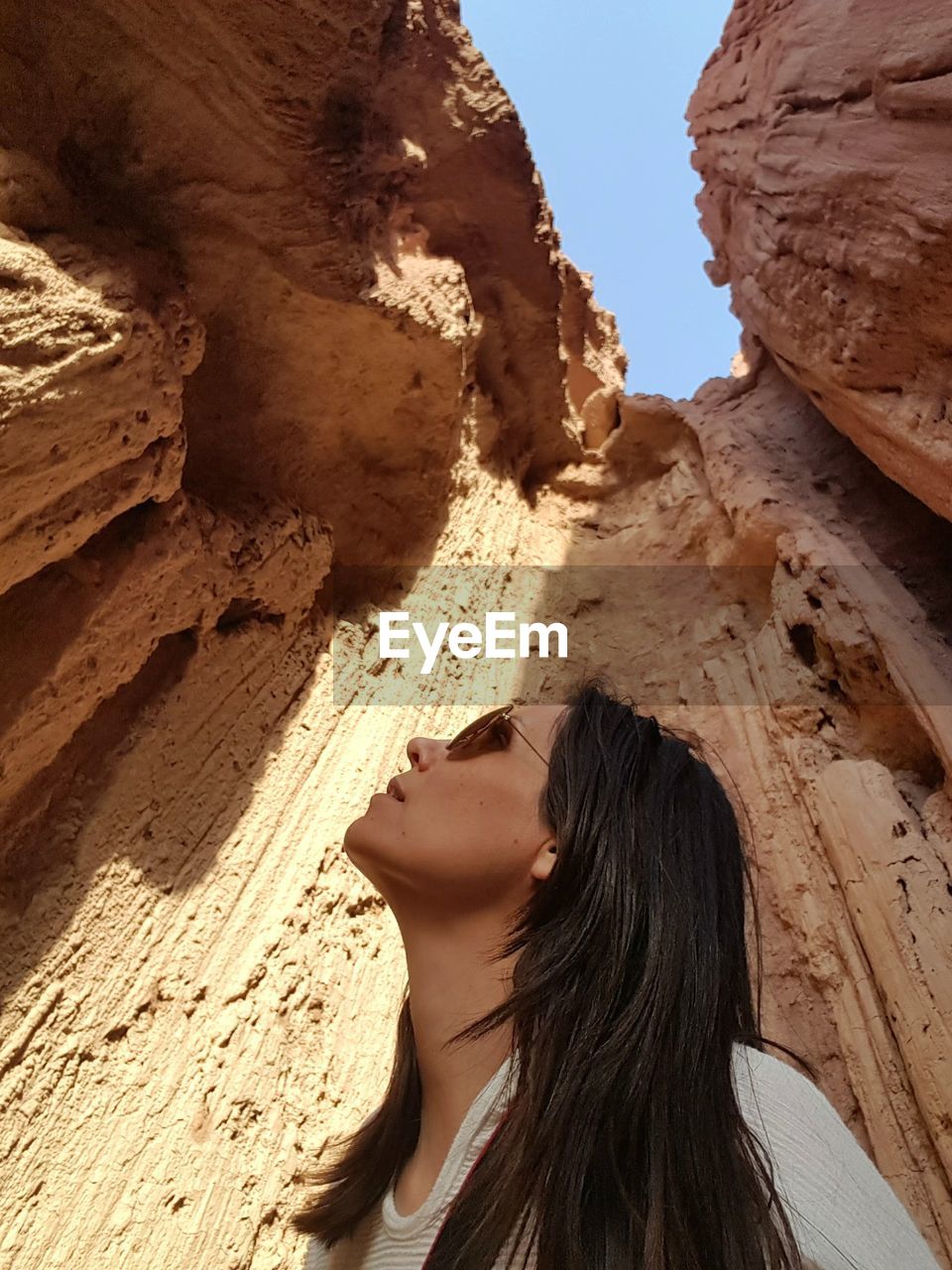 Low angle view of mature woman wearing sunglasses standing against rock formation