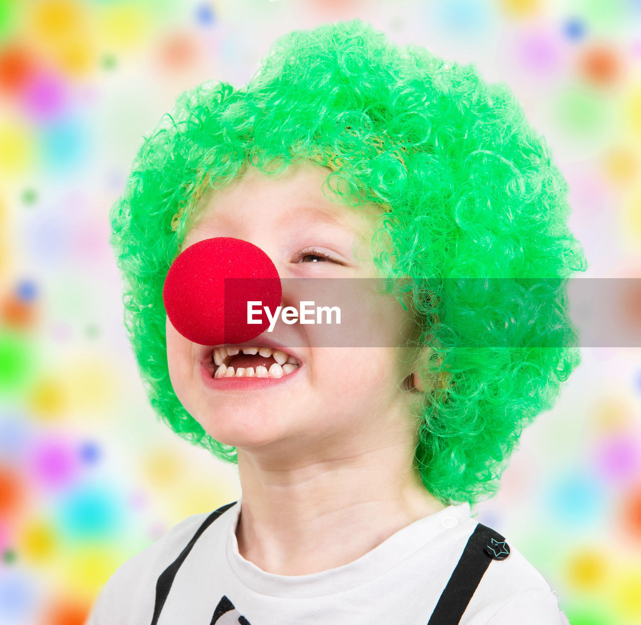 Close-up of boy wearing clowns nose and green wig