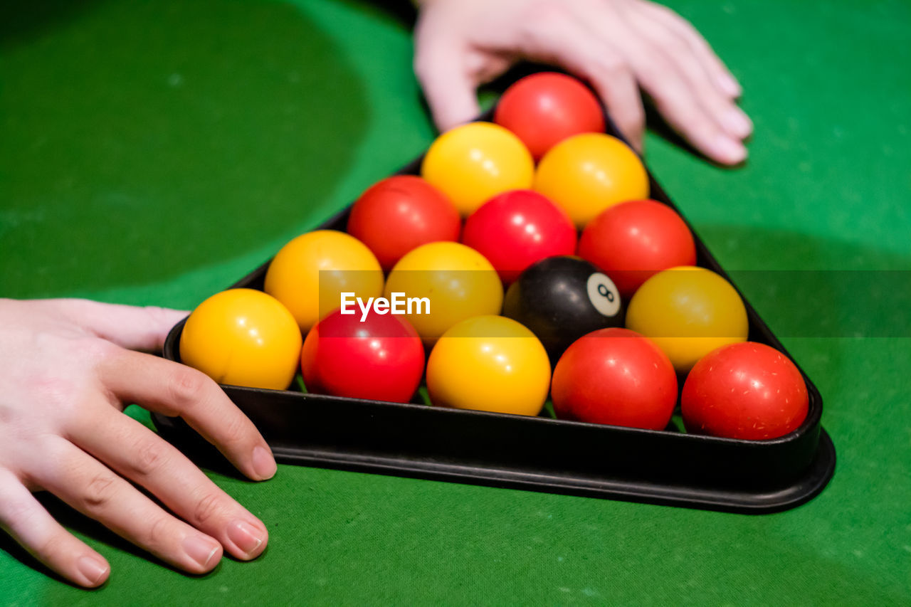 Cropped hands of woman holding pool balls on table