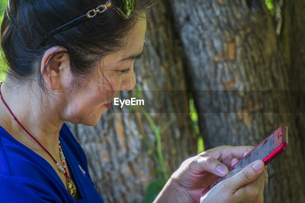 SIDE VIEW OF WOMAN USING MOBILE PHONE