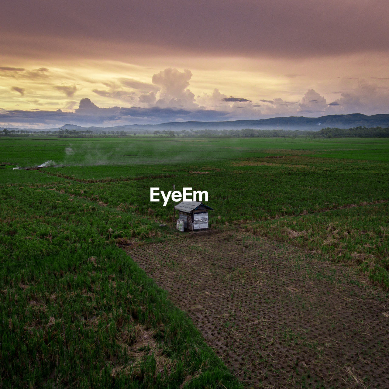 BUILT STRUCTURE ON FIELD AGAINST SKY DURING SUNSET