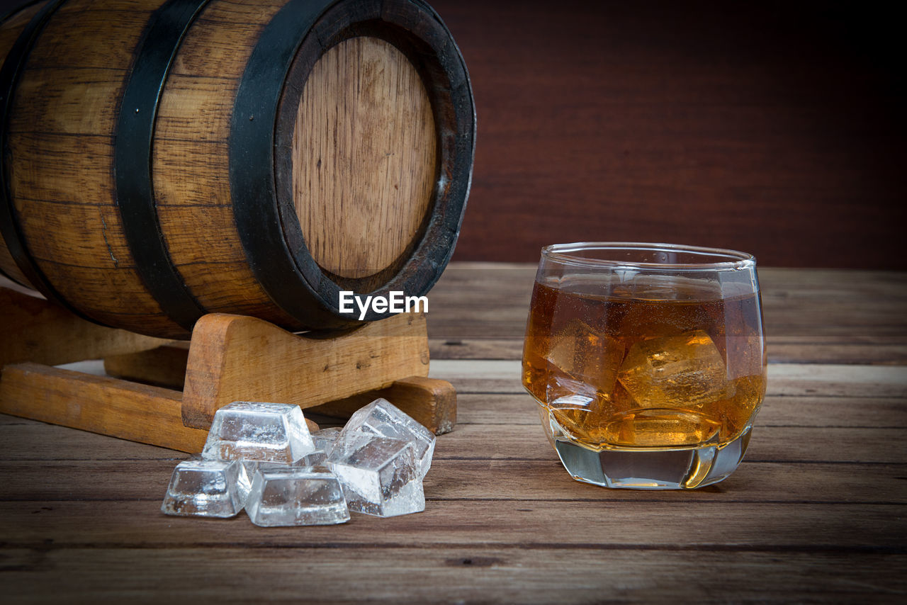 Close-up of ice cubes and whiskey in glass on table