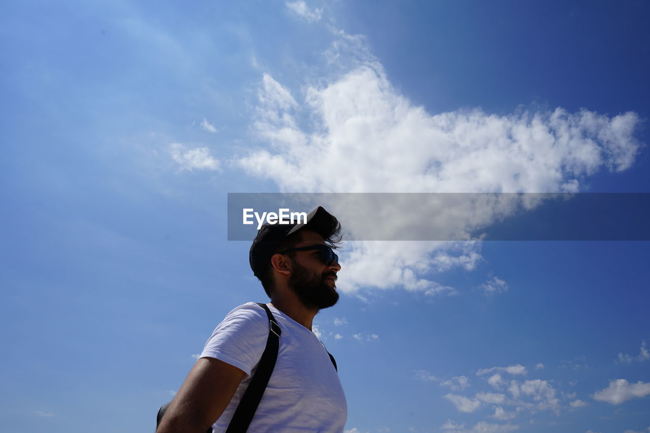 LOW ANGLE VIEW OF YOUNG MAN LOOKING AWAY