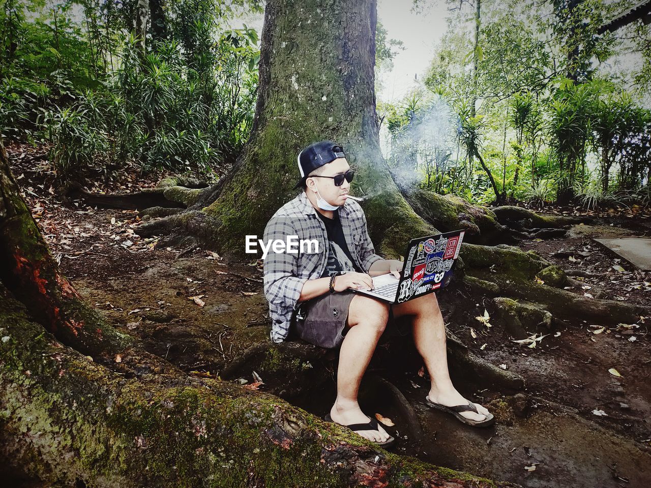 FULL LENGTH OF WOMAN SITTING ON TREE TRUNK