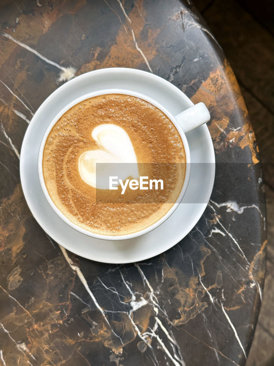 Top view of cup of cappuccino coffee with latte art on marble table background.