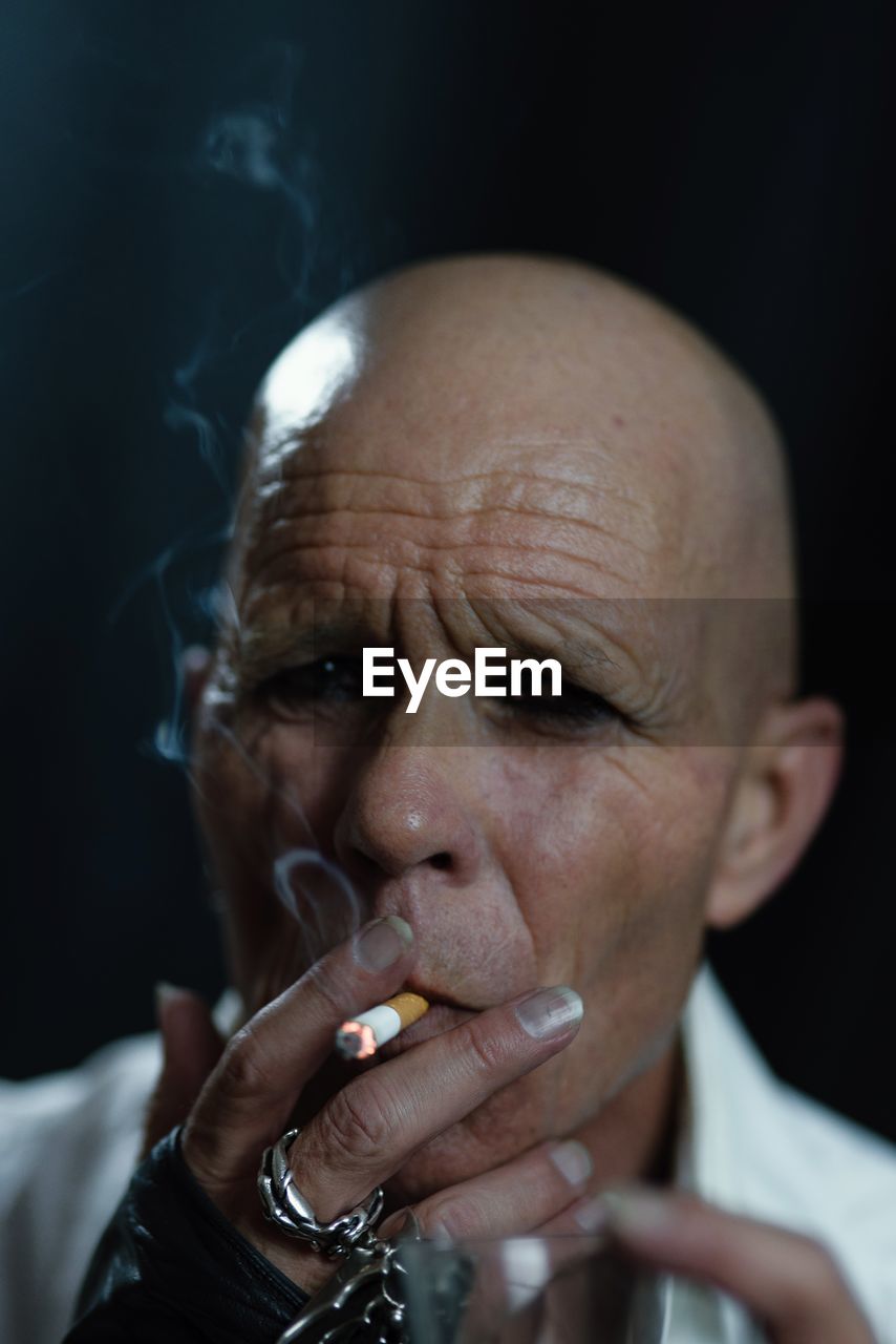 Close-up portrait of bald man smoking cigarette