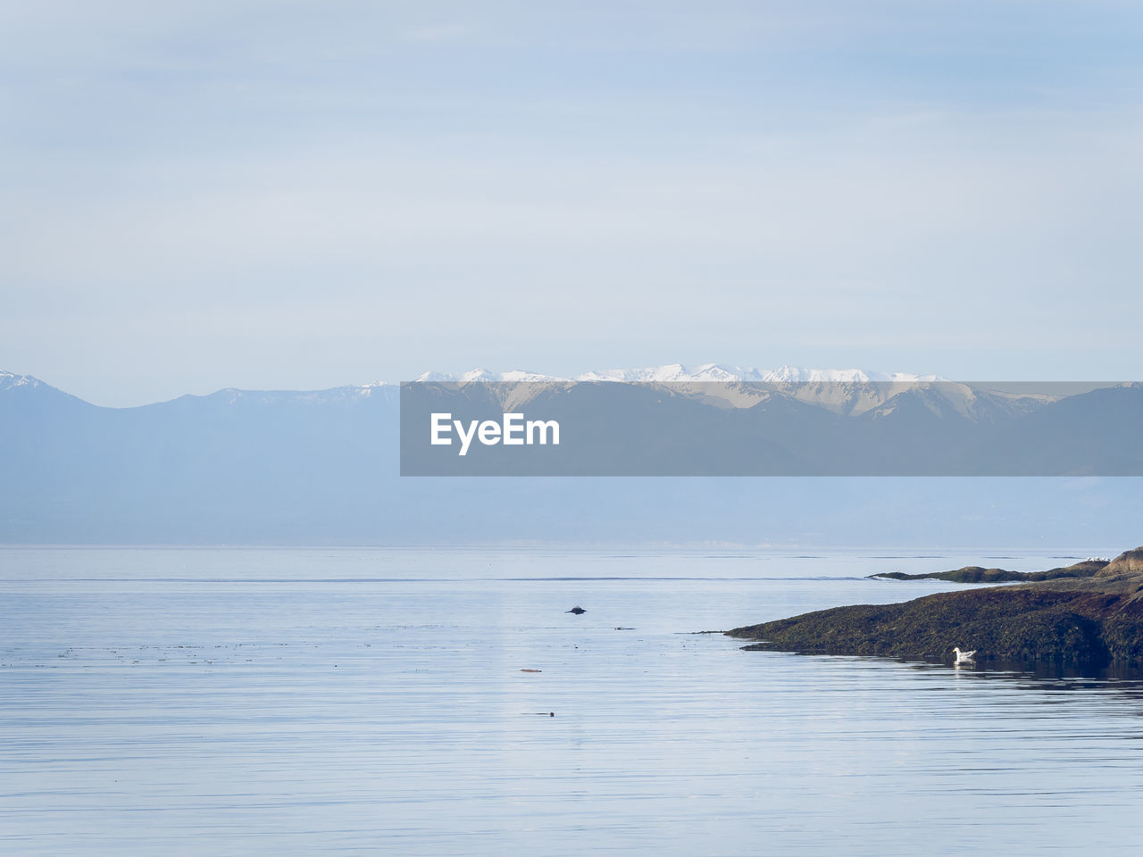 Scenic view of sea and mountains against sky