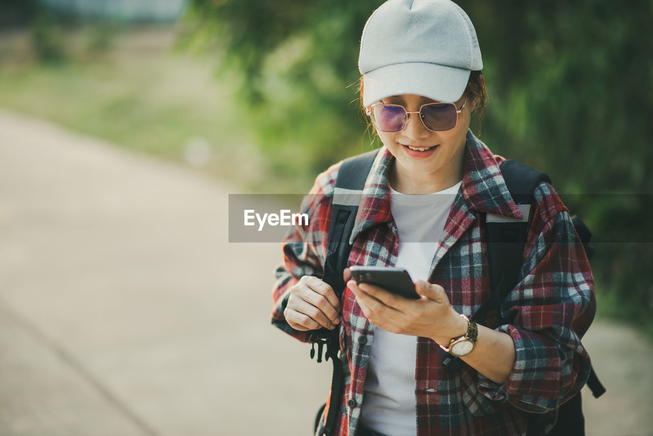 Portrait of young woman standing outdoors using myphone