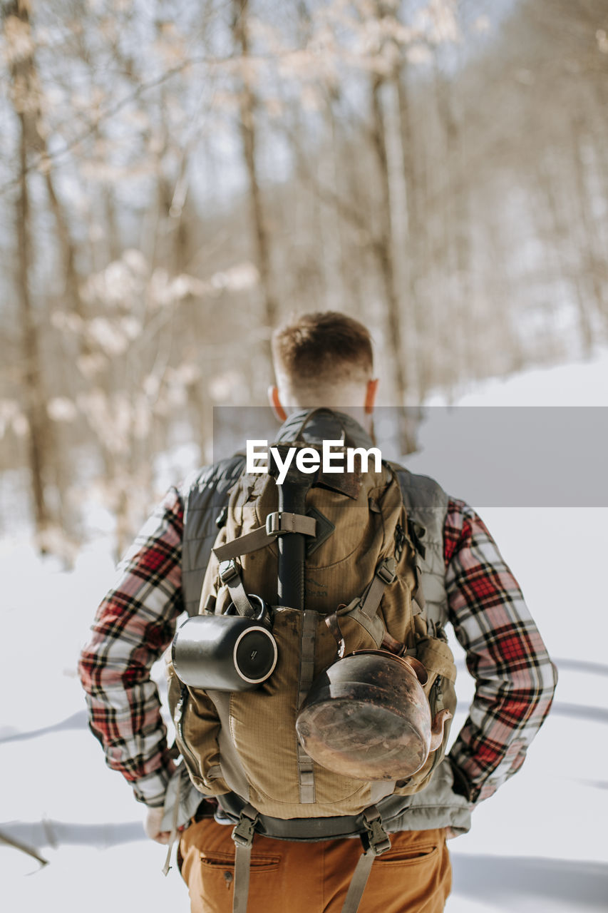 Closeup of man wearing pack and flannel in snow covered woods