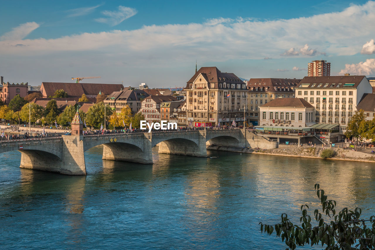 Bridge over river by buildings against sky in city