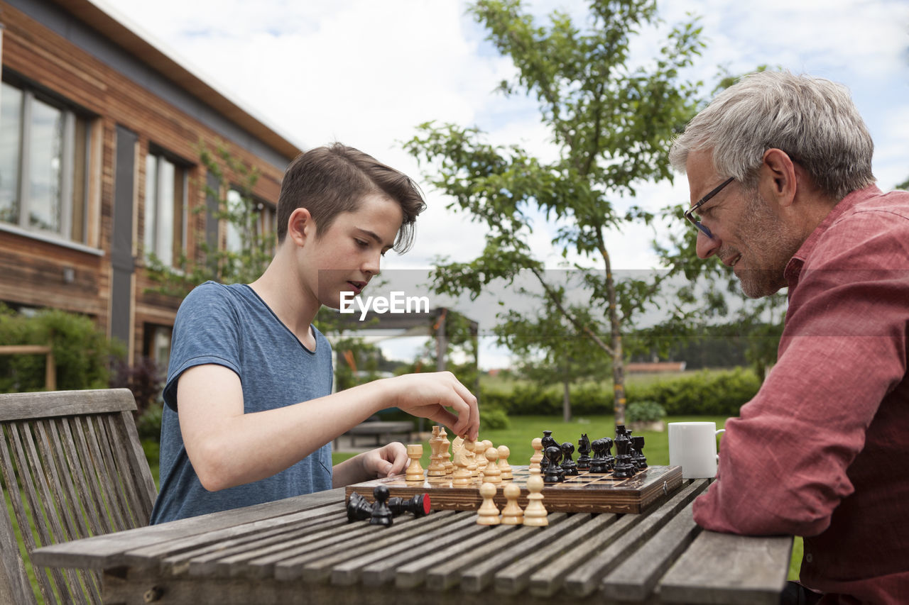 Father and son playing chess in garden