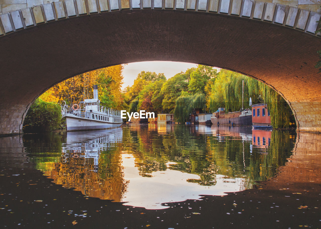 Boats in canal under arch bridge