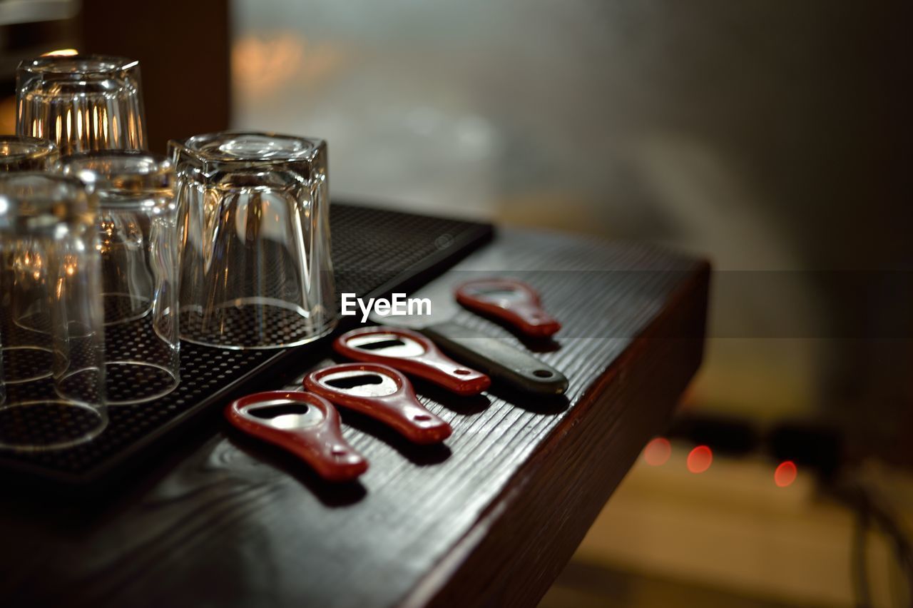 Glasses by bottle openers on wooden table