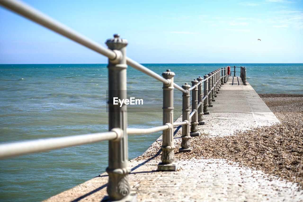 Close-up of railing by sea against sky