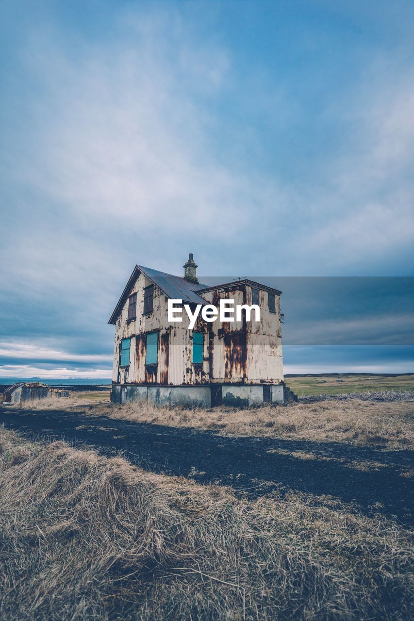 Abandoned building on field against sky