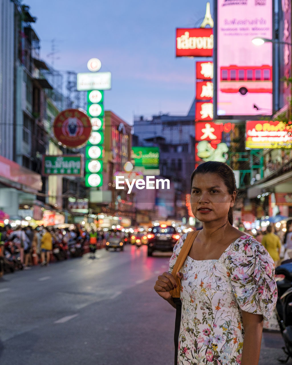 portrait of smiling young woman standing on street in city