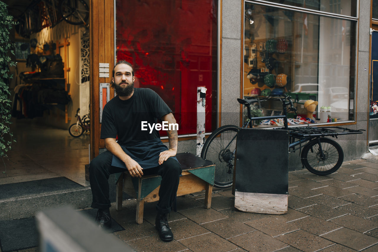 Male mechanic sitting on table outside retail store