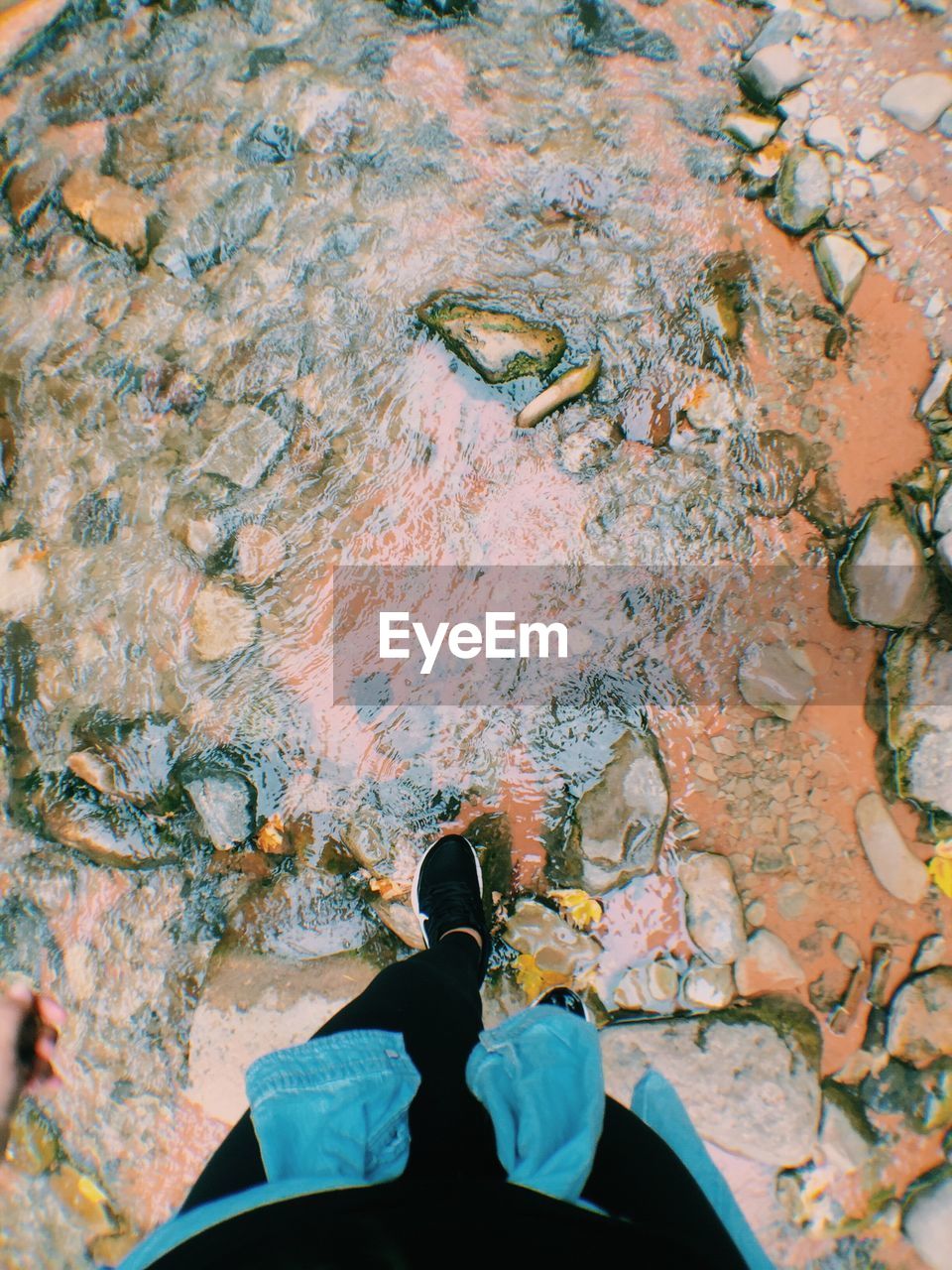 LOW SECTION OF MAN STANDING ON WATER SURFACE