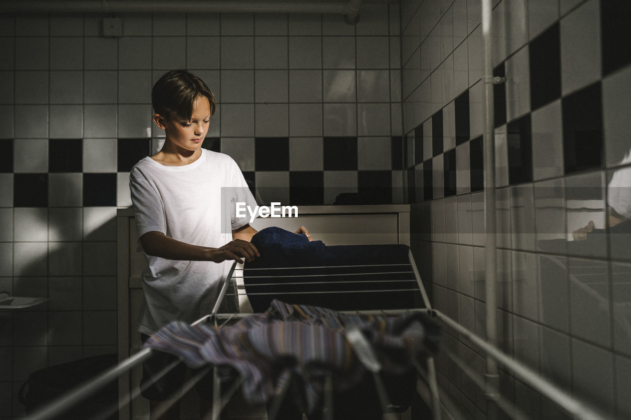 Boy doing laundry in utility room