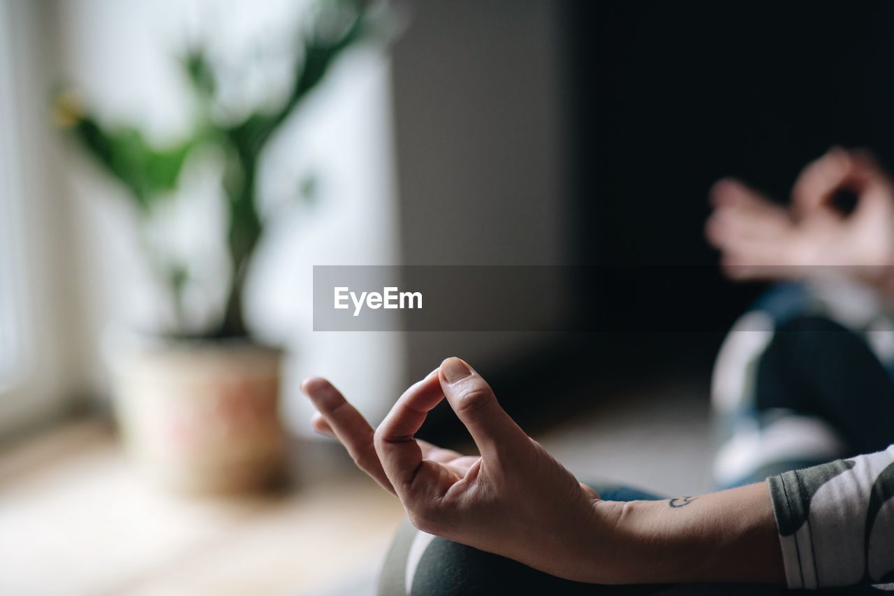 Midsection of woman meditating at home