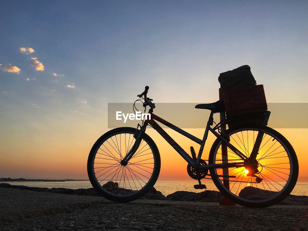 Bicycle at beach against sky during sunset
