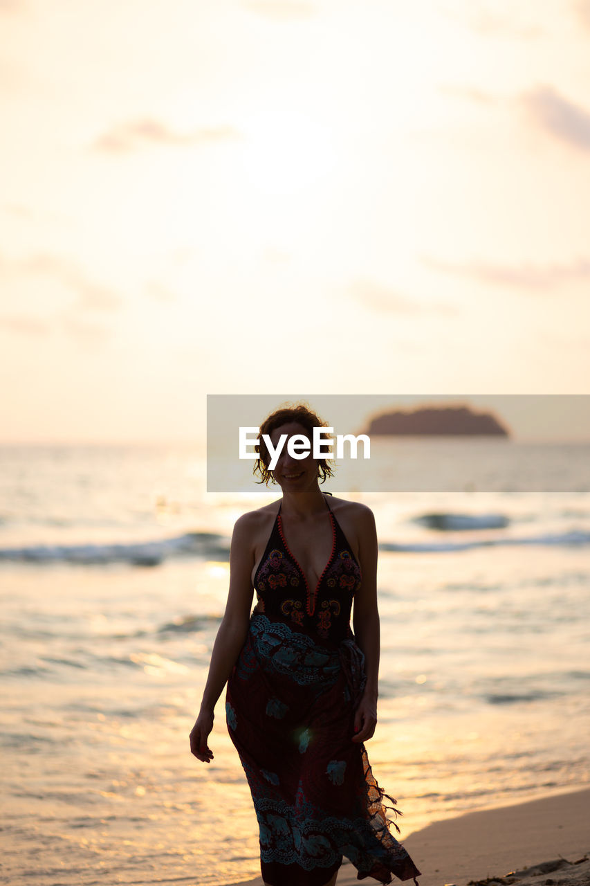 Woman walking on beach during sunset