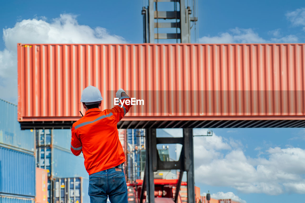 Engineers are overseeing the transportation of cargo with containers inside the warehouse. 