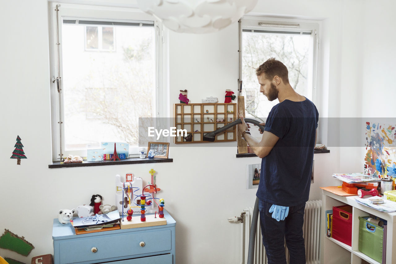 Man vacuuming small shelves