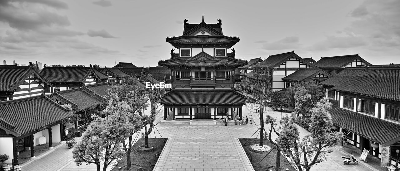 People at temple against cloudy sky