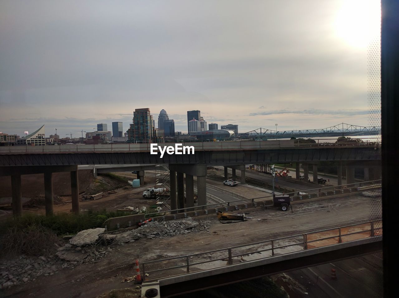 Bridge and buildings against cloudy sky during sunny day