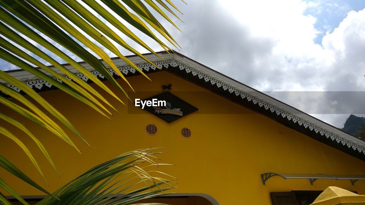 LOW ANGLE VIEW OF YELLOW BUILDING AGAINST CLOUDY SKY