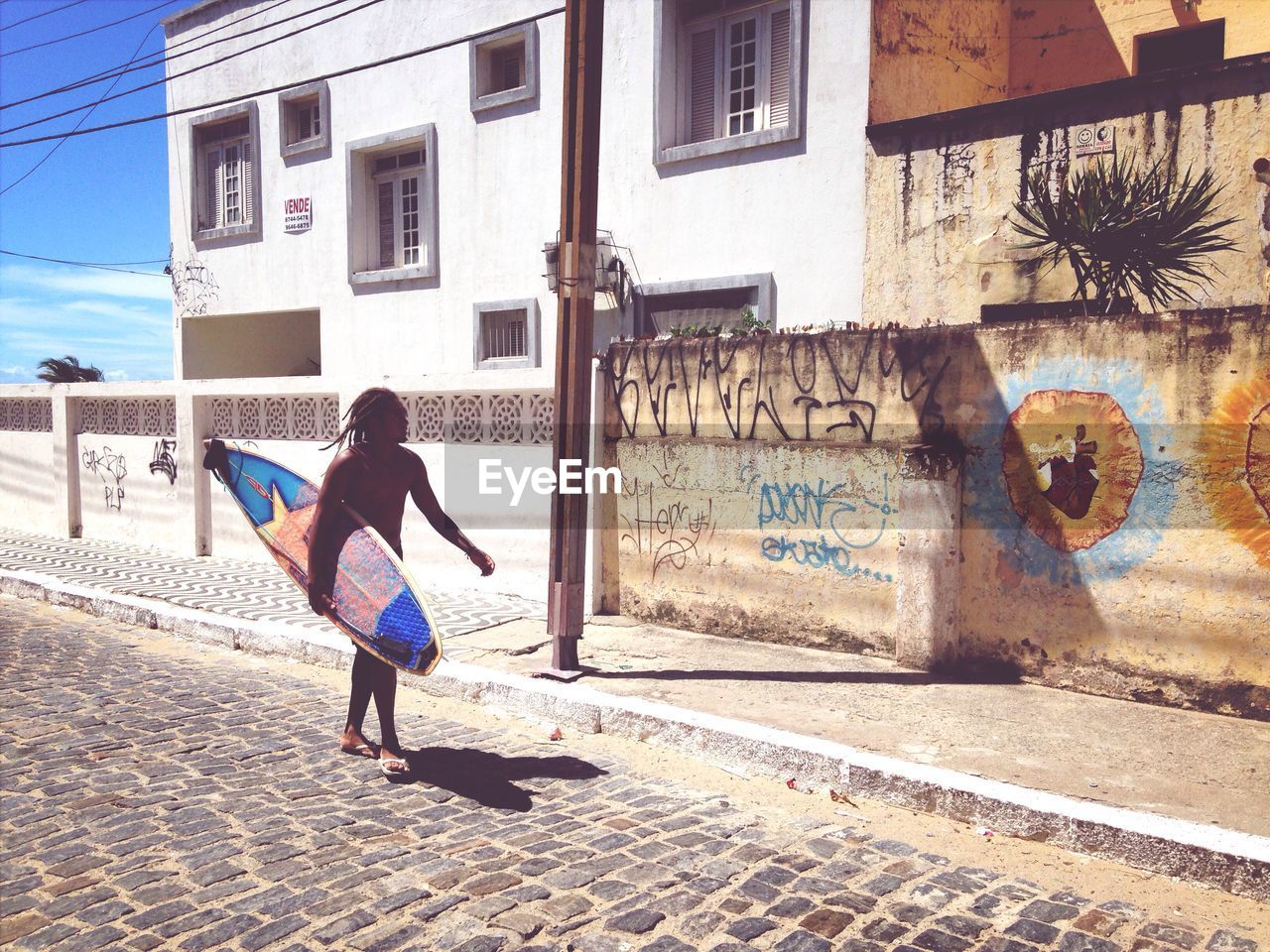 FULL LENGTH OF YOUNG WOMAN STANDING ON BUILDING