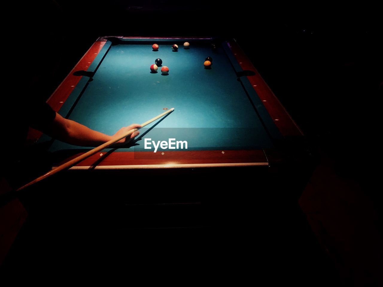 Cropped image of man playing pool in dark