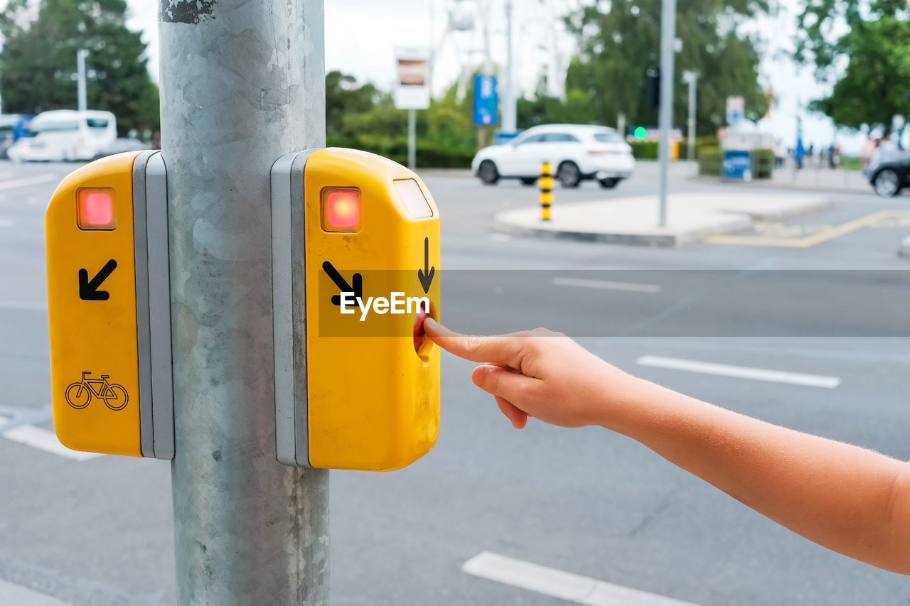 cropped hand of person holding red sign on street