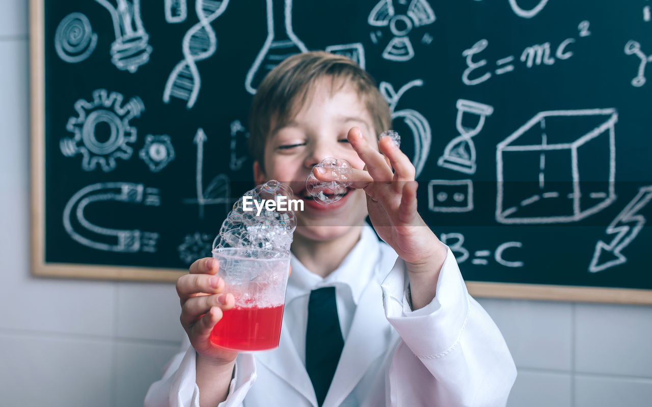 Boy wearing lap coat while standing in classroom