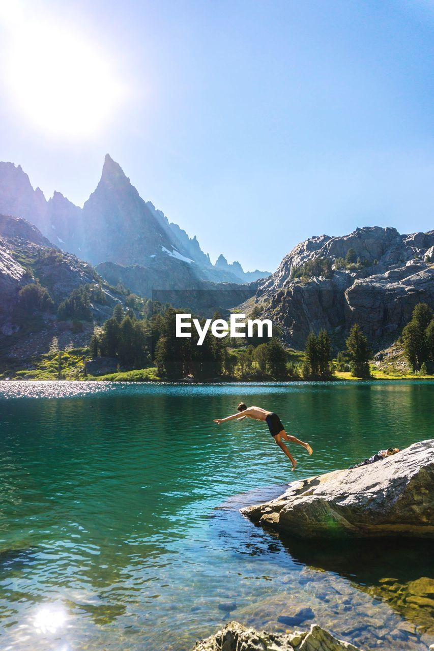 Man diving into mammoth lakes against sky during sunny day