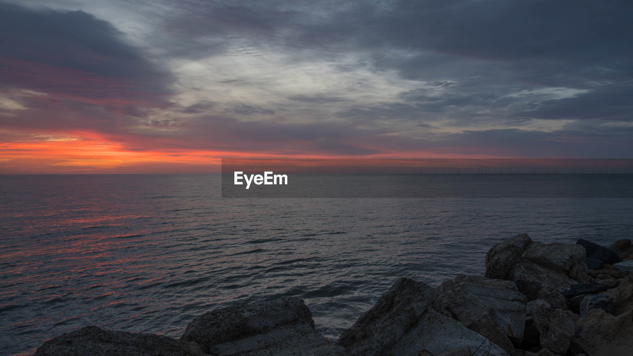 sky, water, sea, cloud, beauty in nature, sunset, scenics - nature, horizon, horizon over water, nature, rock, tranquility, land, dramatic sky, ocean, seascape, beach, environment, tranquil scene, dawn, coast, landscape, shore, cloudscape, no people, evening, idyllic, outdoors, urban skyline, travel, travel destinations, sun, afterglow, coastline, wave, motion, moody sky, orange color