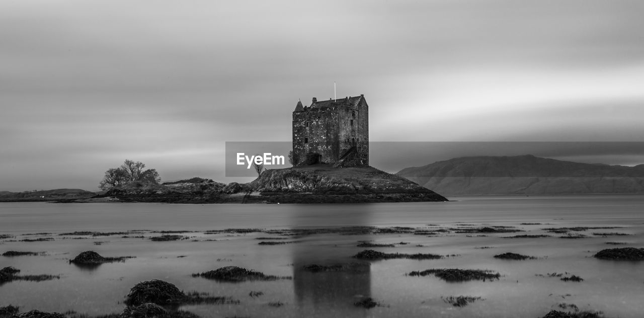 Old ruin in sea against cloudy sky