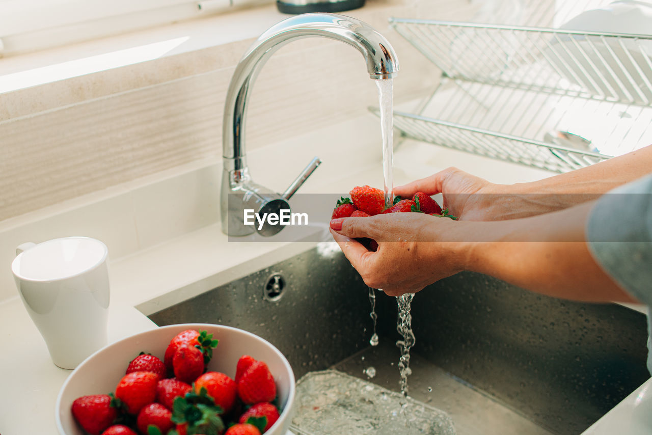 Close up of female hands washing vegetables in tap water