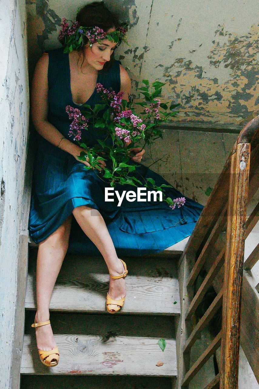 High angle view of beautiful woman with flowers sitting on staircase in building