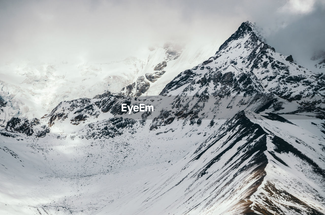 Scenic view of snowcapped mountains against cloudy sky