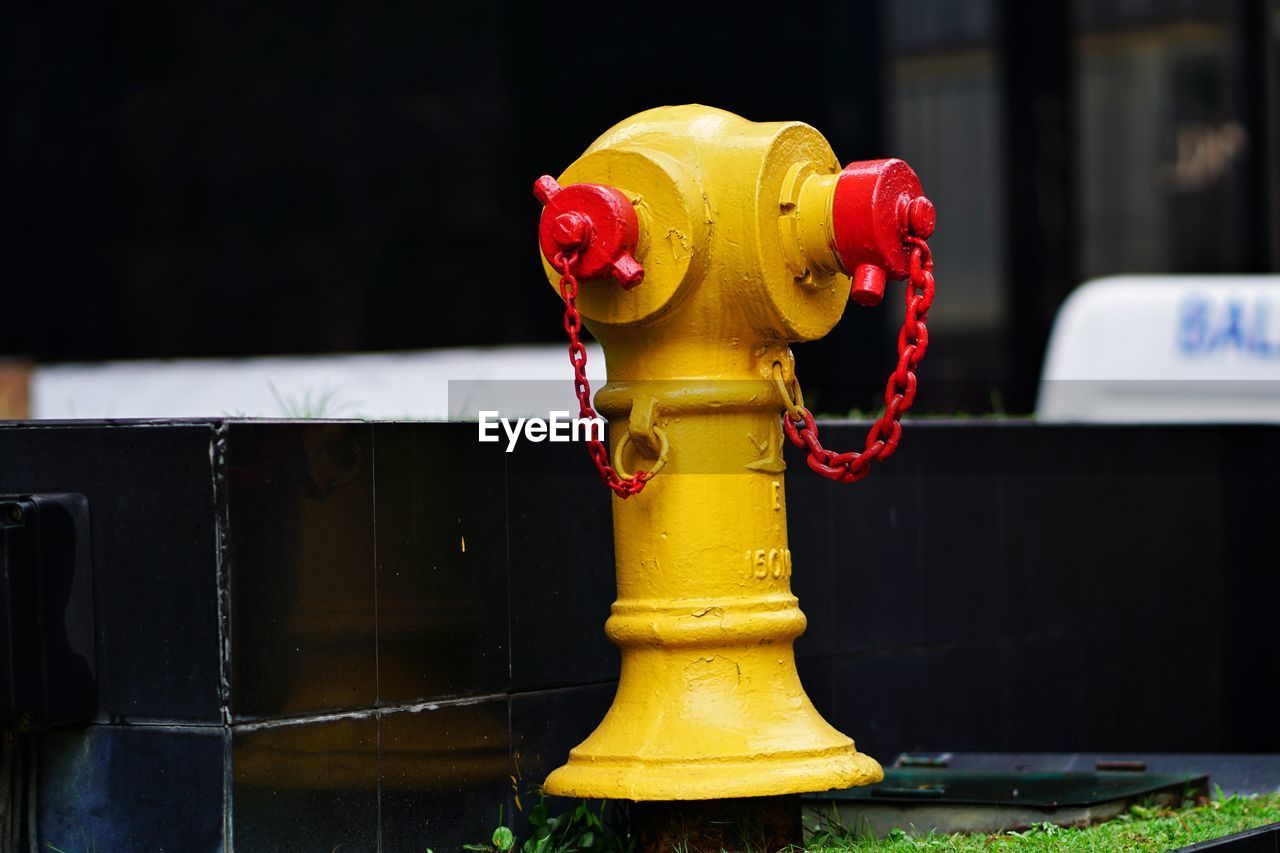 CLOSE-UP OF YELLOW SCULPTURE BY WATER